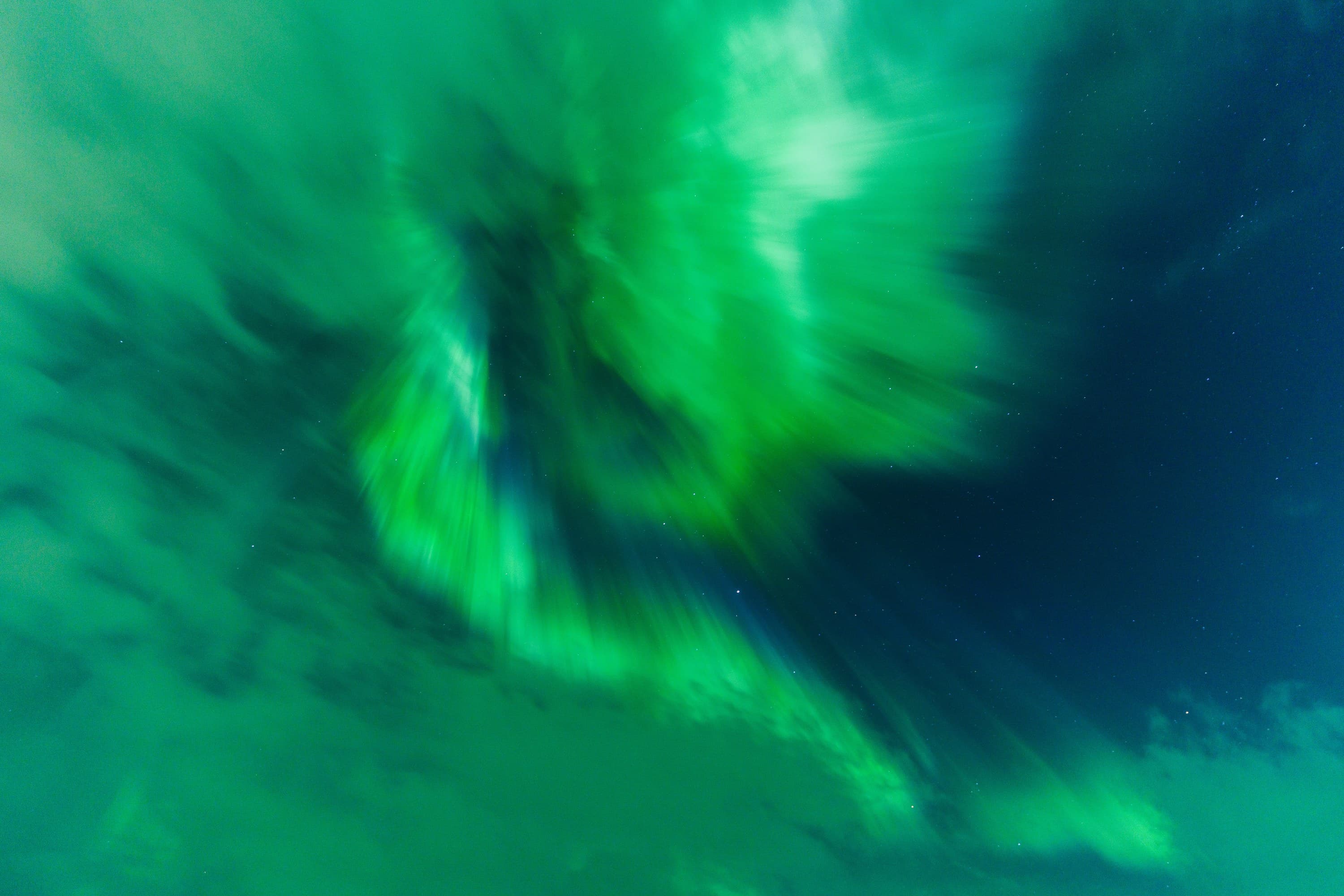 Green aurora unfurling in a feathered arc with lines of motion radiating through the sky.