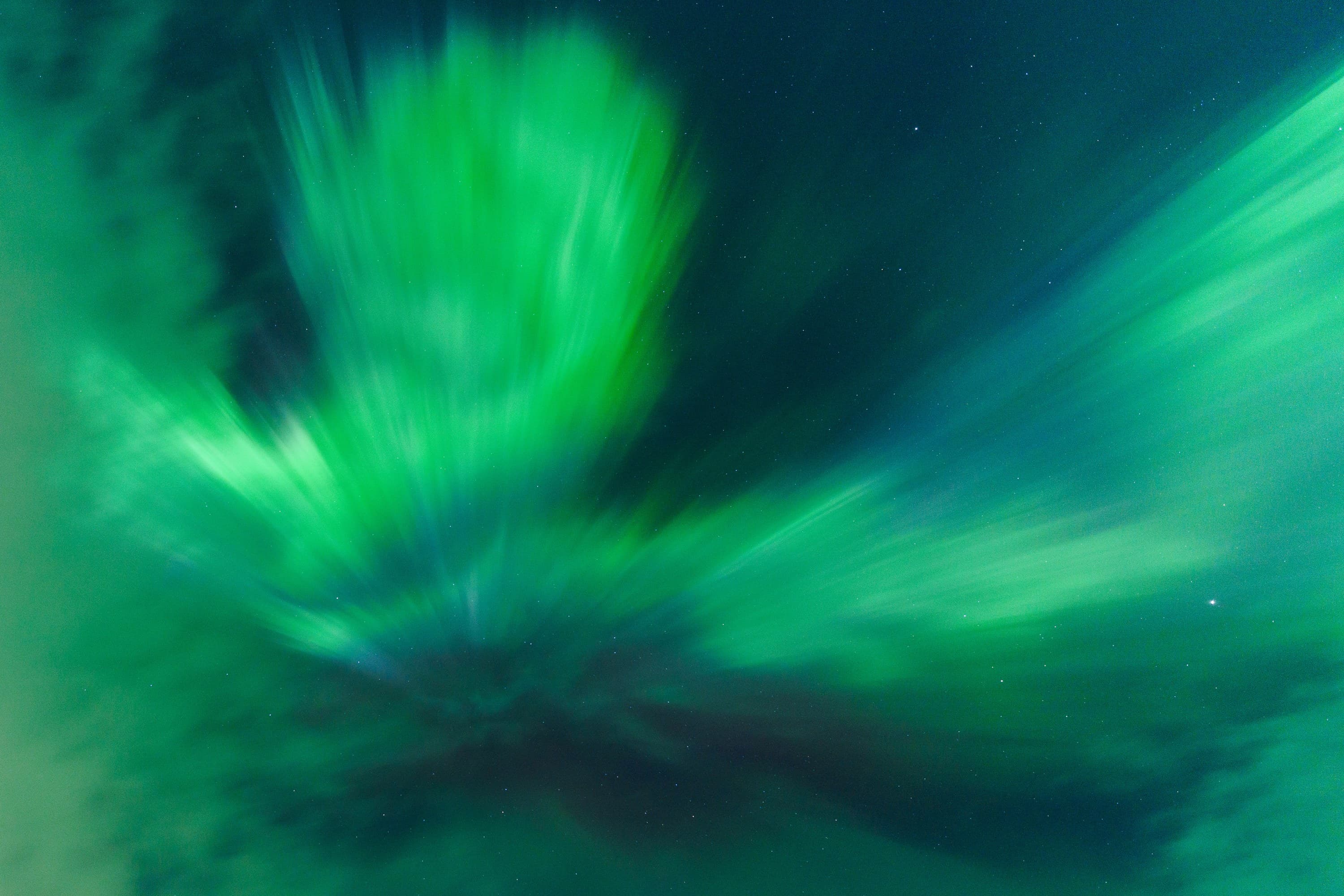 Aurora light rushing outward in green and cyan streaks around a dark centre.