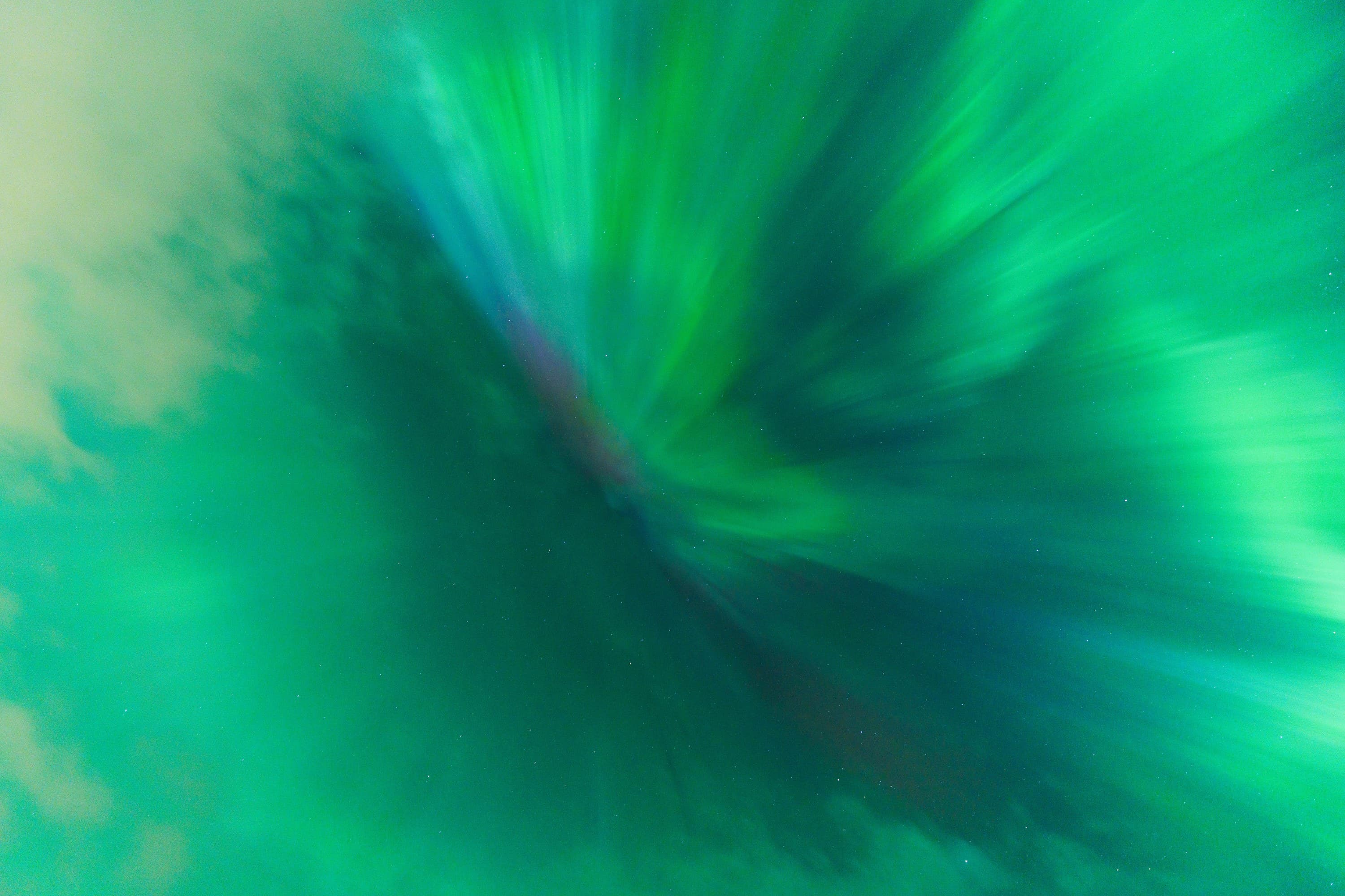 Abstract green and blue aurora radiating from a dark central fold.