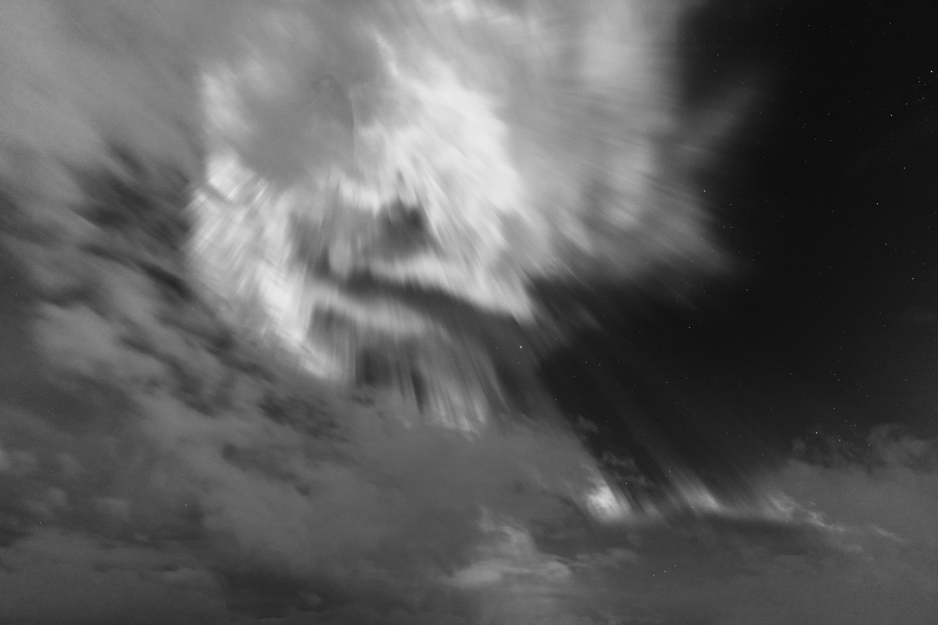 Monochrome clouds and aurora drawn into a turbulent, painterly swirl.