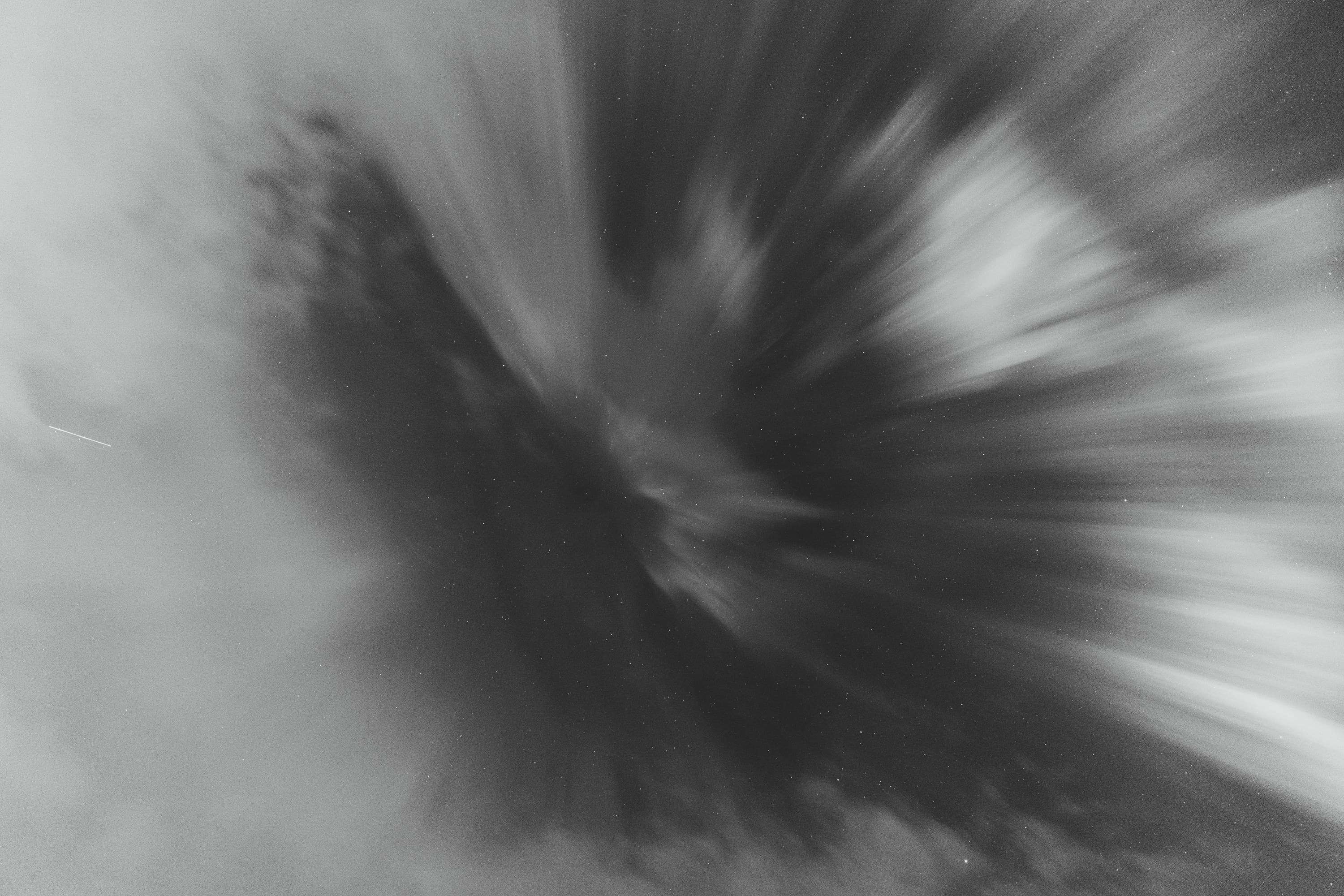 Soft black-and-white rays streaming from a shadowed centre like an afterimage.