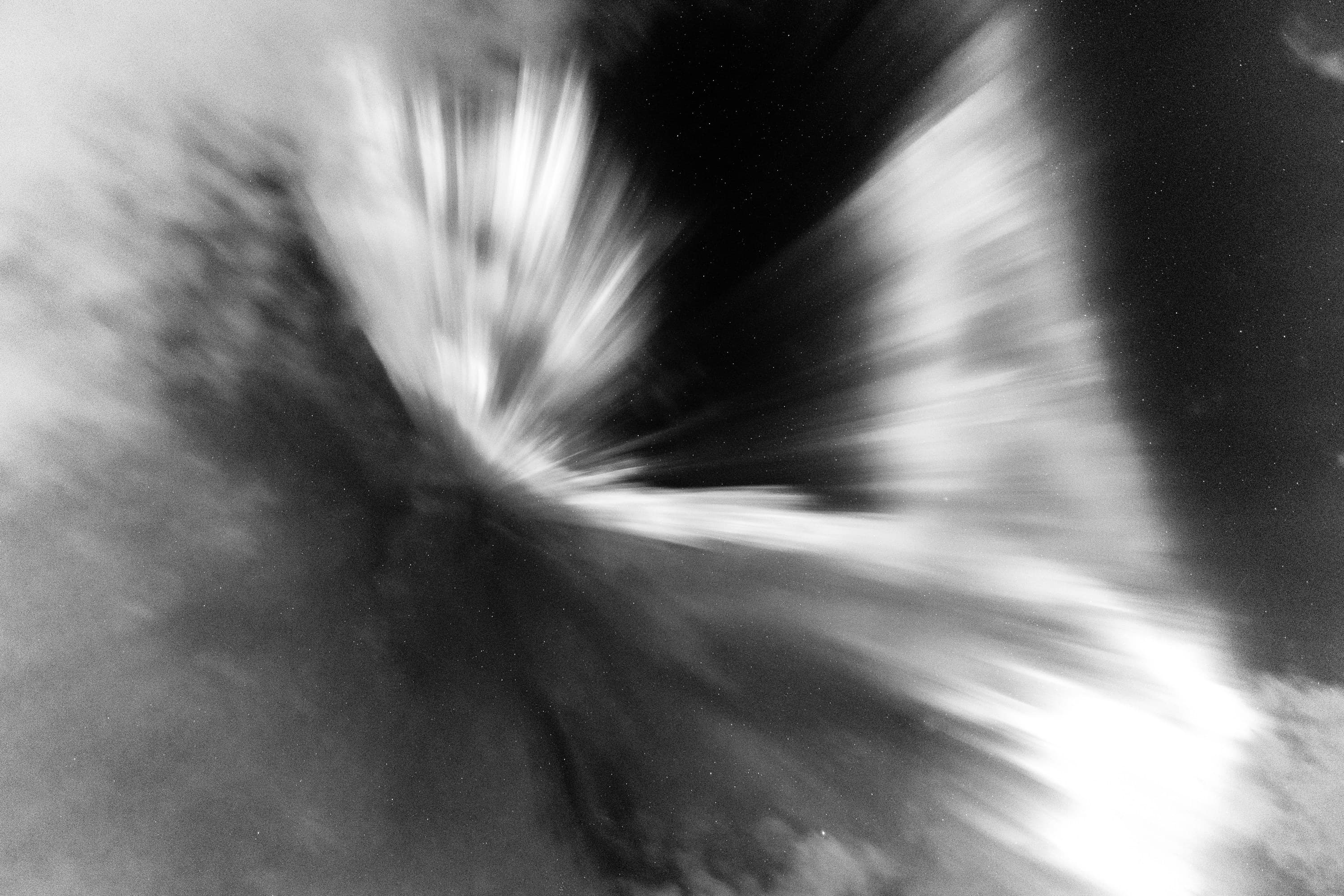 Dramatic monochrome aurora exploding into bright radial bands across the frame.